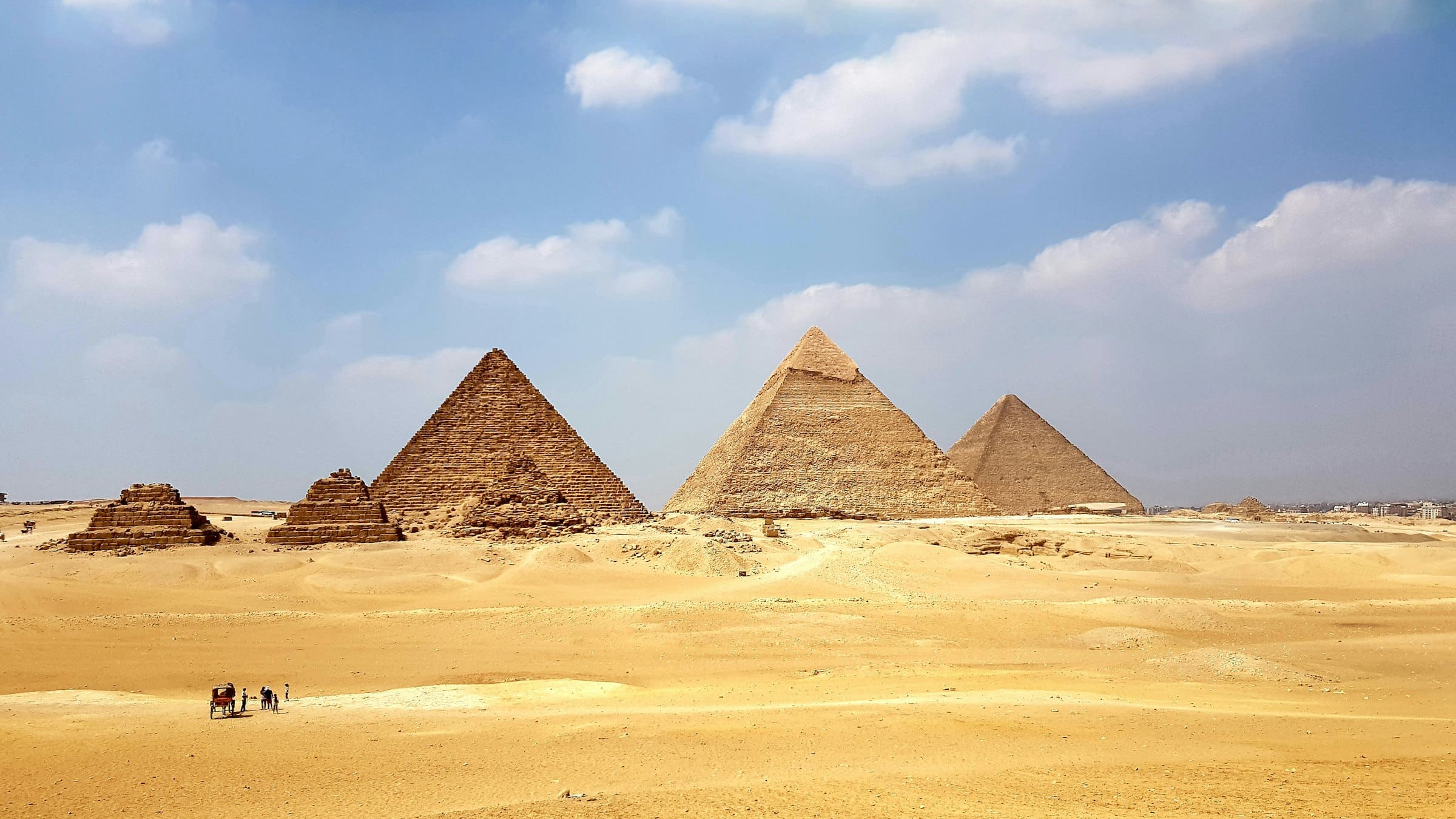 The three pyramids of Giza rising above the desert under a blue sky